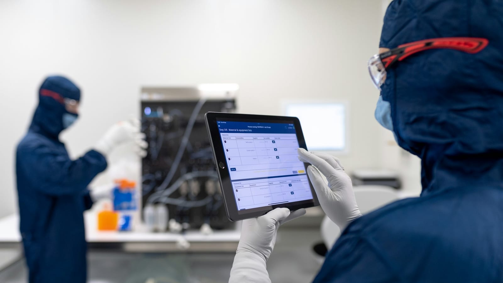 Technicien en combinaison de protection lisant un formulaire d'intervention structuré sur une tablette, en environnement industriel